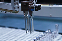 A closeup of automated scientific testing equipment in a medical laboratory facility being used to sample glass vials